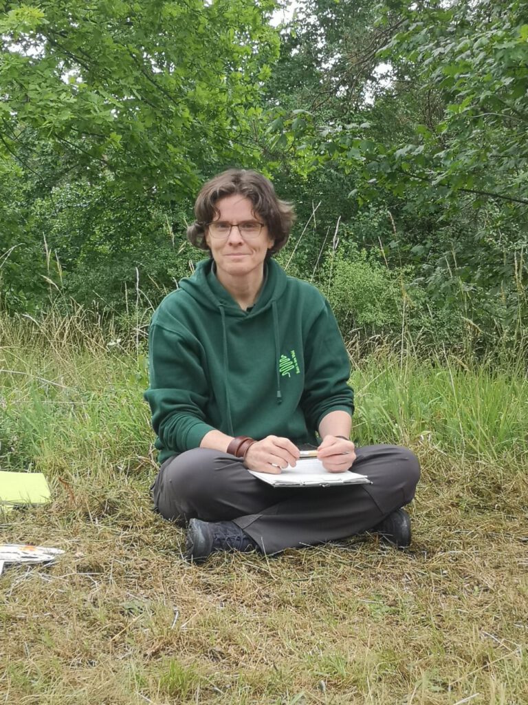 Sibylle Appoldt von Raus in den Wald sitz lächelnd im Schneidersitz im Gras